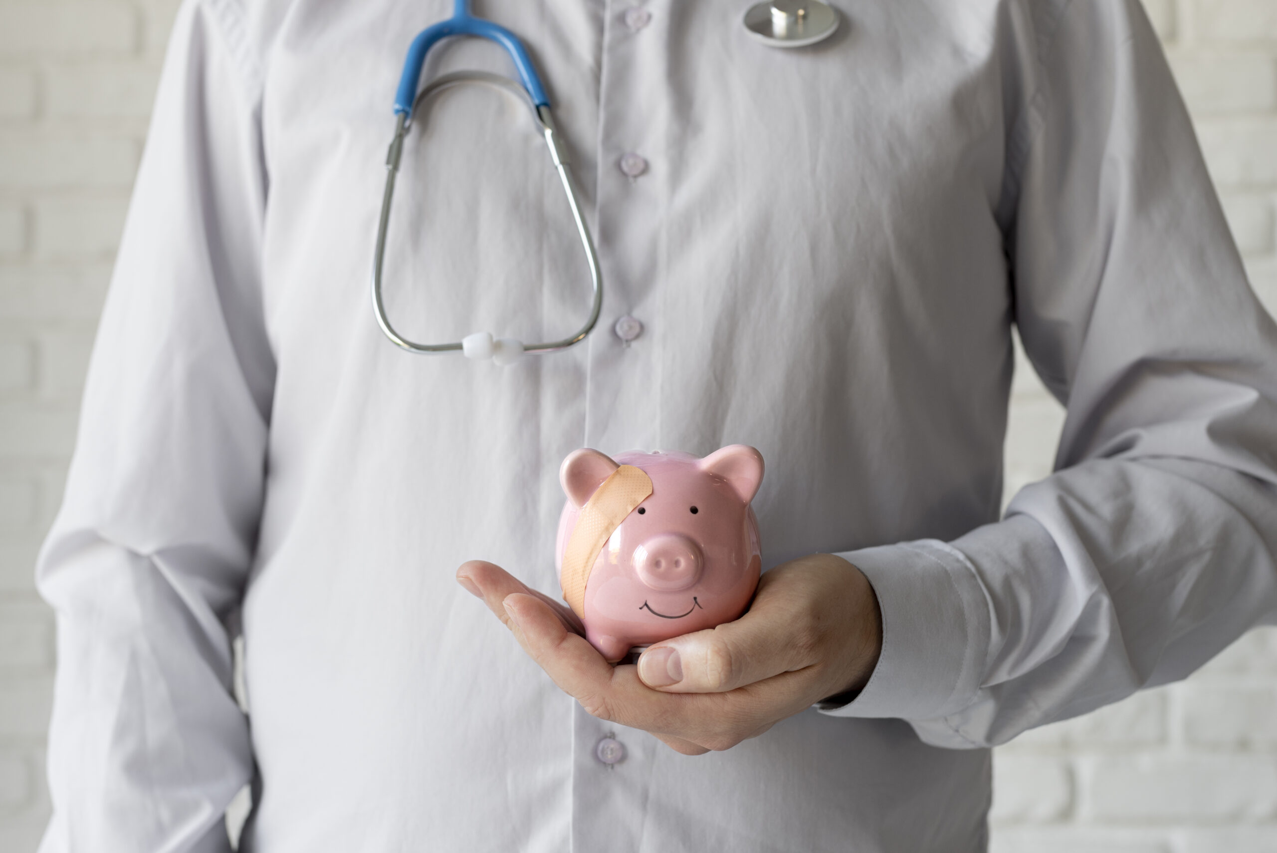 Doctor holding a bandaged piggy bank, representing efforts to reduce chronic disease costs in healthcare.
